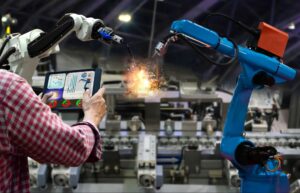 Engineer with tablet controlling the production of factory parts manufacturing industry robots and mechanical arm