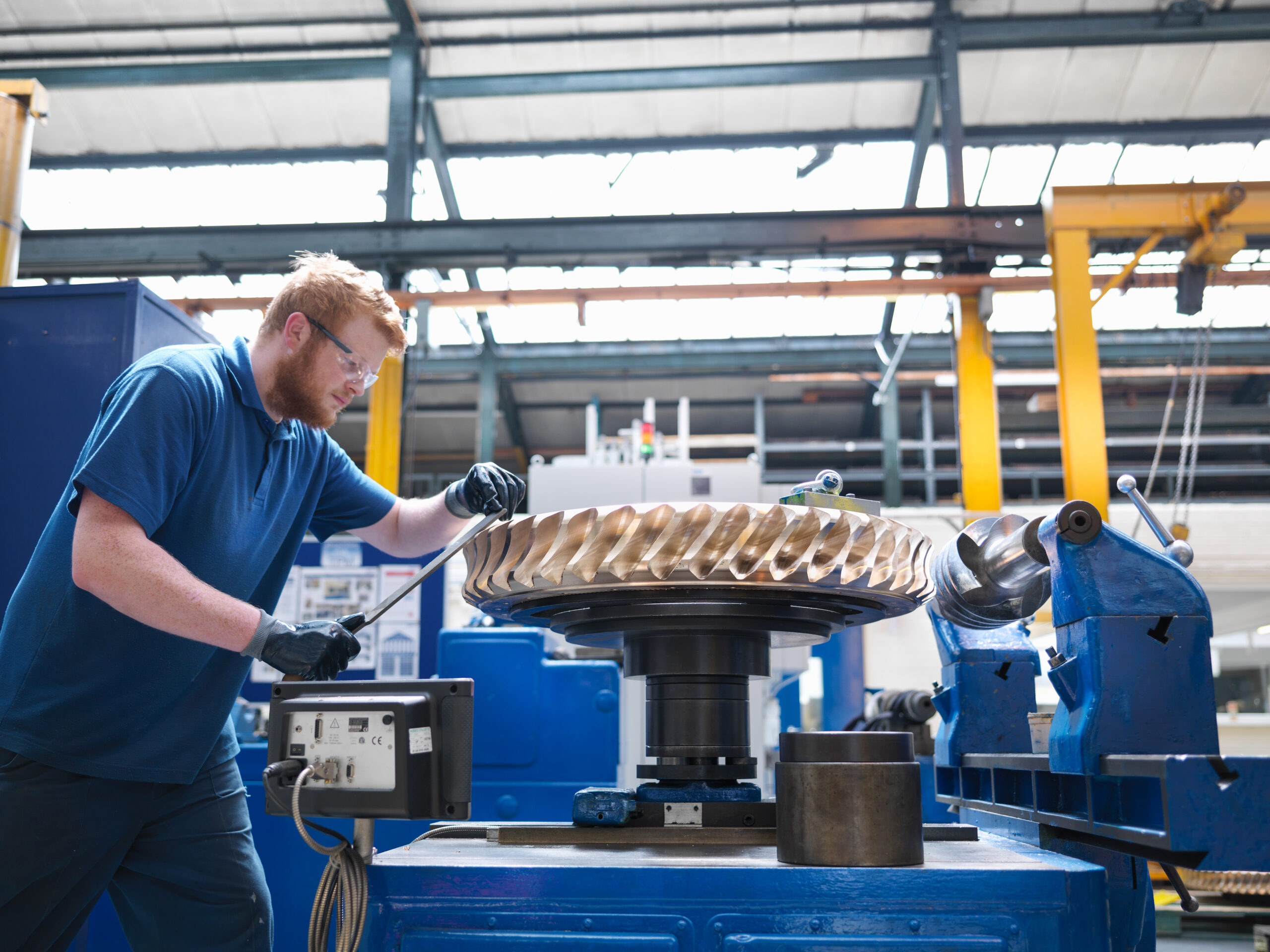 Skilled technician operating precision machinery for gear manufacturing, part of Martin Control's engineering and technical services.