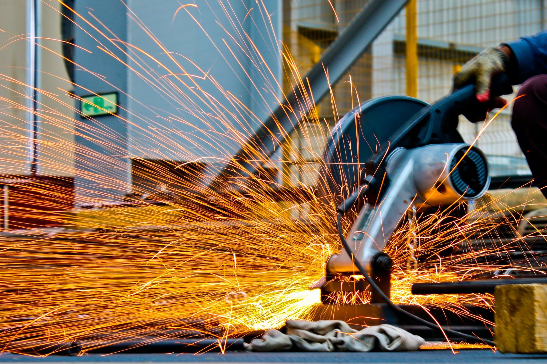 Skilled worker using angle grinder in metal fabrication, showcasing Martin Control's expertise in industrial manufacturing processes.